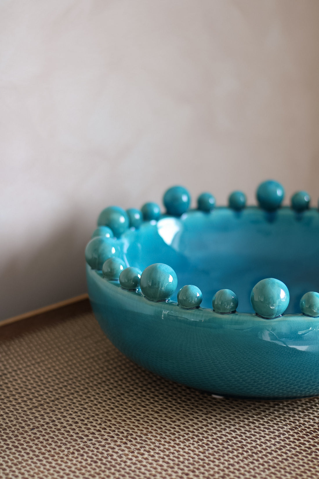 aqua bowl with bobble edge detailing on a textured surface