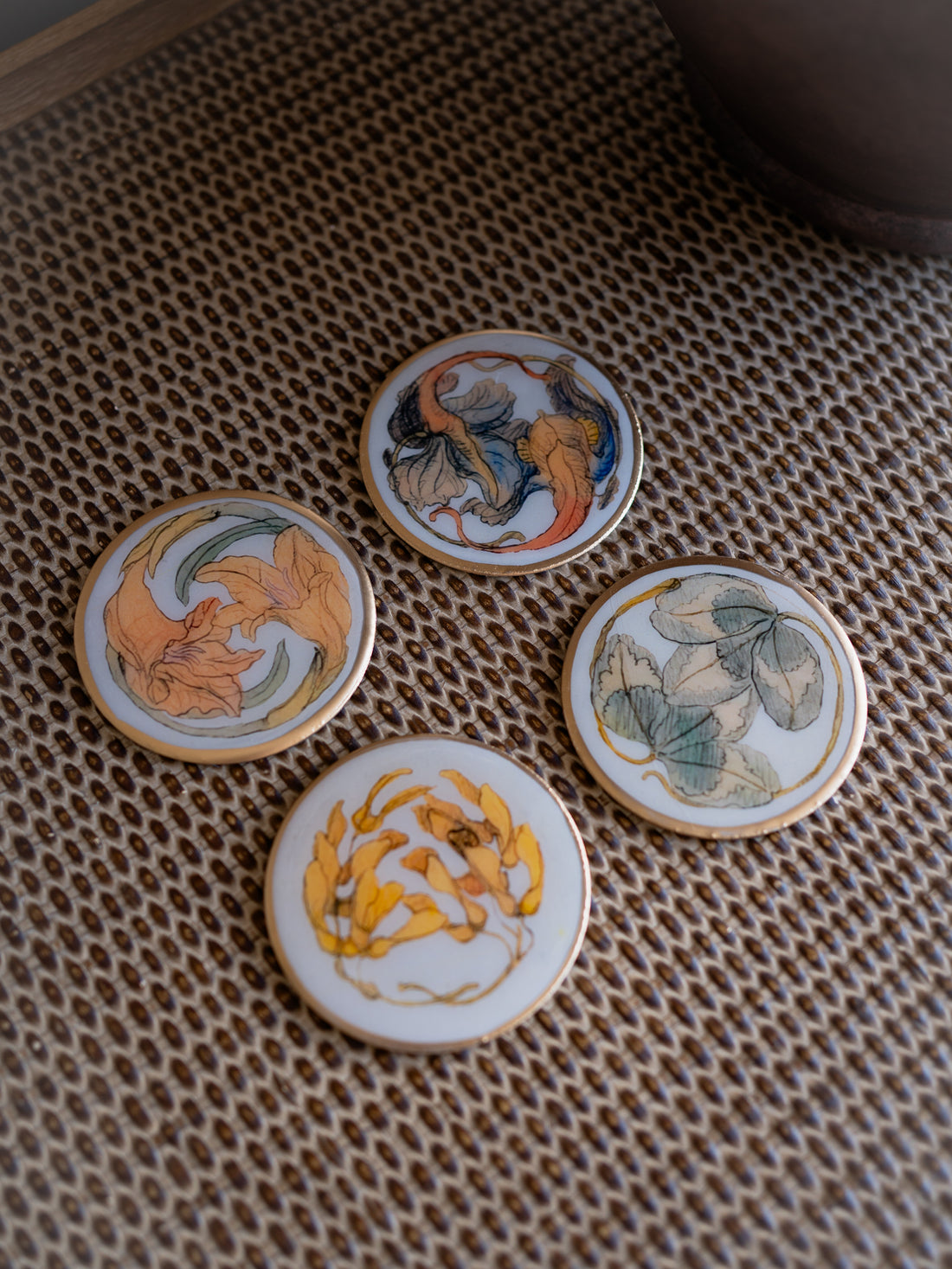 Four decorative coasters with artistic designs on a textured surface
