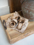 Wooden tray with white washed rattan napkin rings with beaded edge detailing items on a white surface