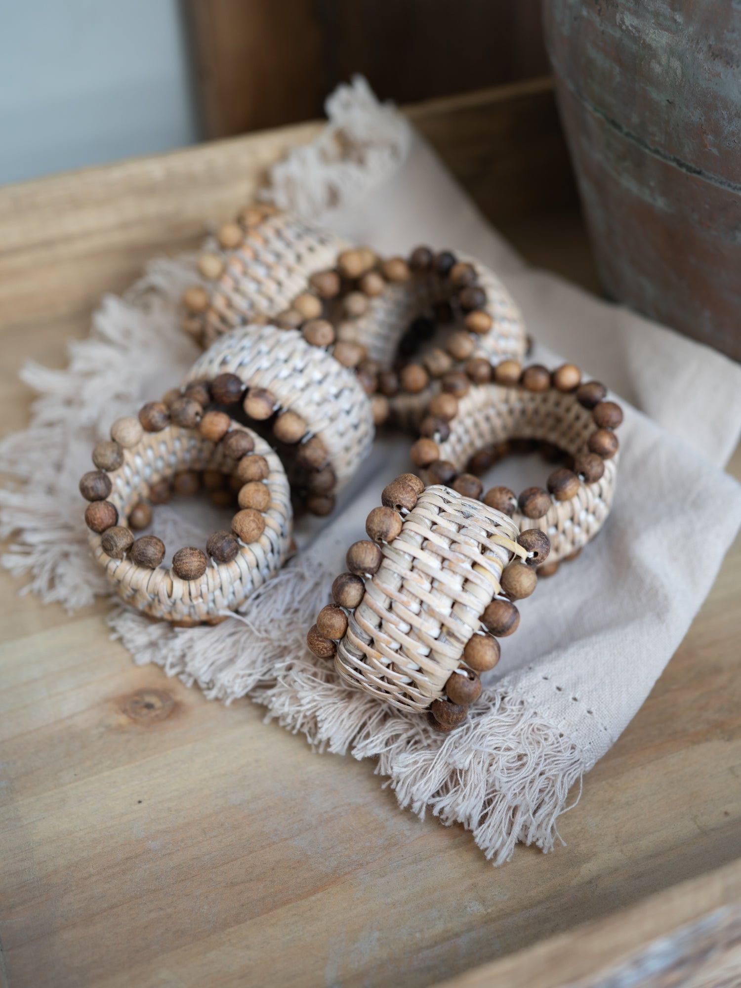 Wooden beaded napkin rings on a textured fabric surface with a wooden background