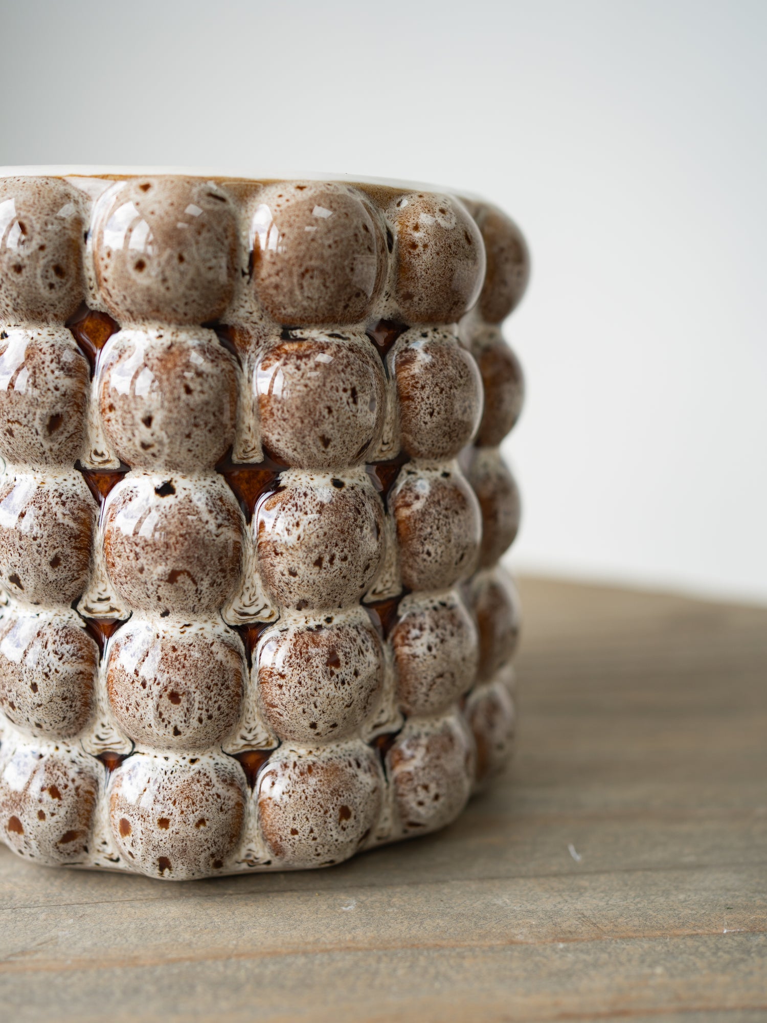 Ceramic plant pot with textured, bubble-like design on a wooden surface.