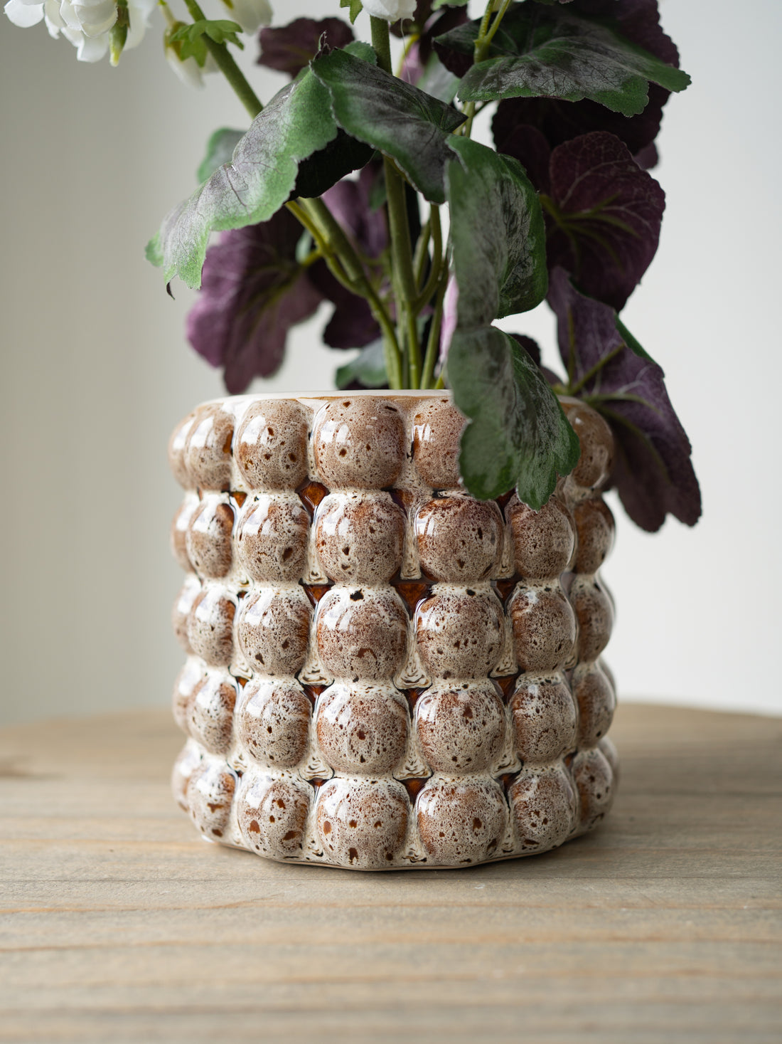 Decorative ceramic plant pot with a textured surface on a wooden table.