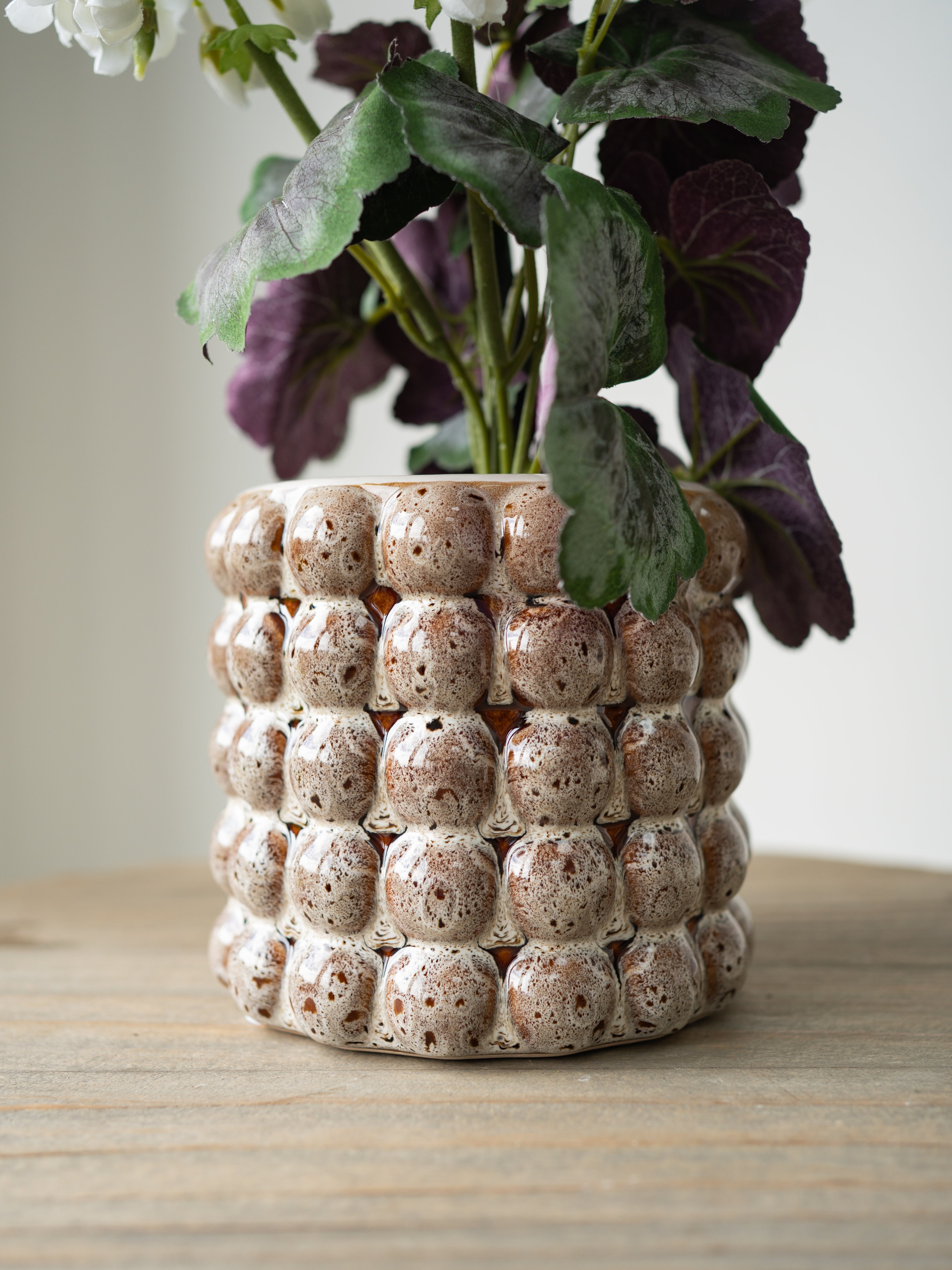 Decorative ceramic plant pot with a textured surface on a wooden table.