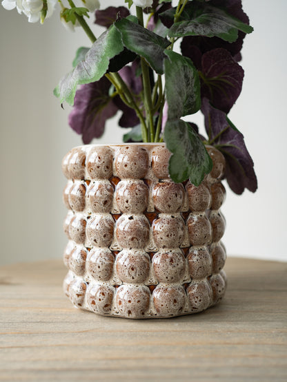 Decorative ceramic plant pot with a textured surface on a wooden table.