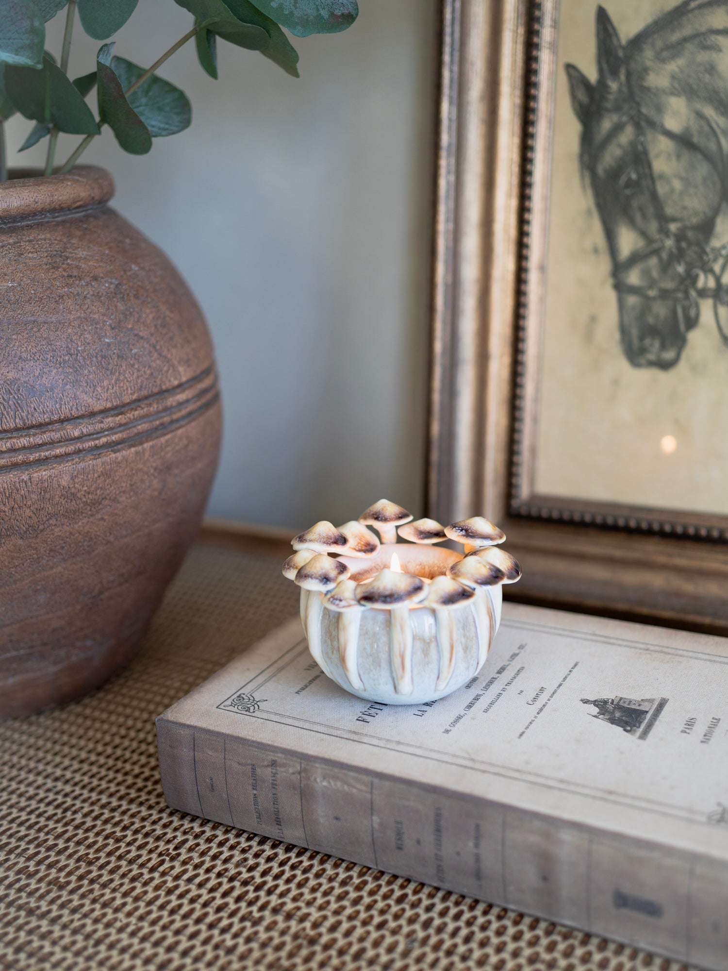 Decorative mushroom candle holder on a book with a horse portrait in the background