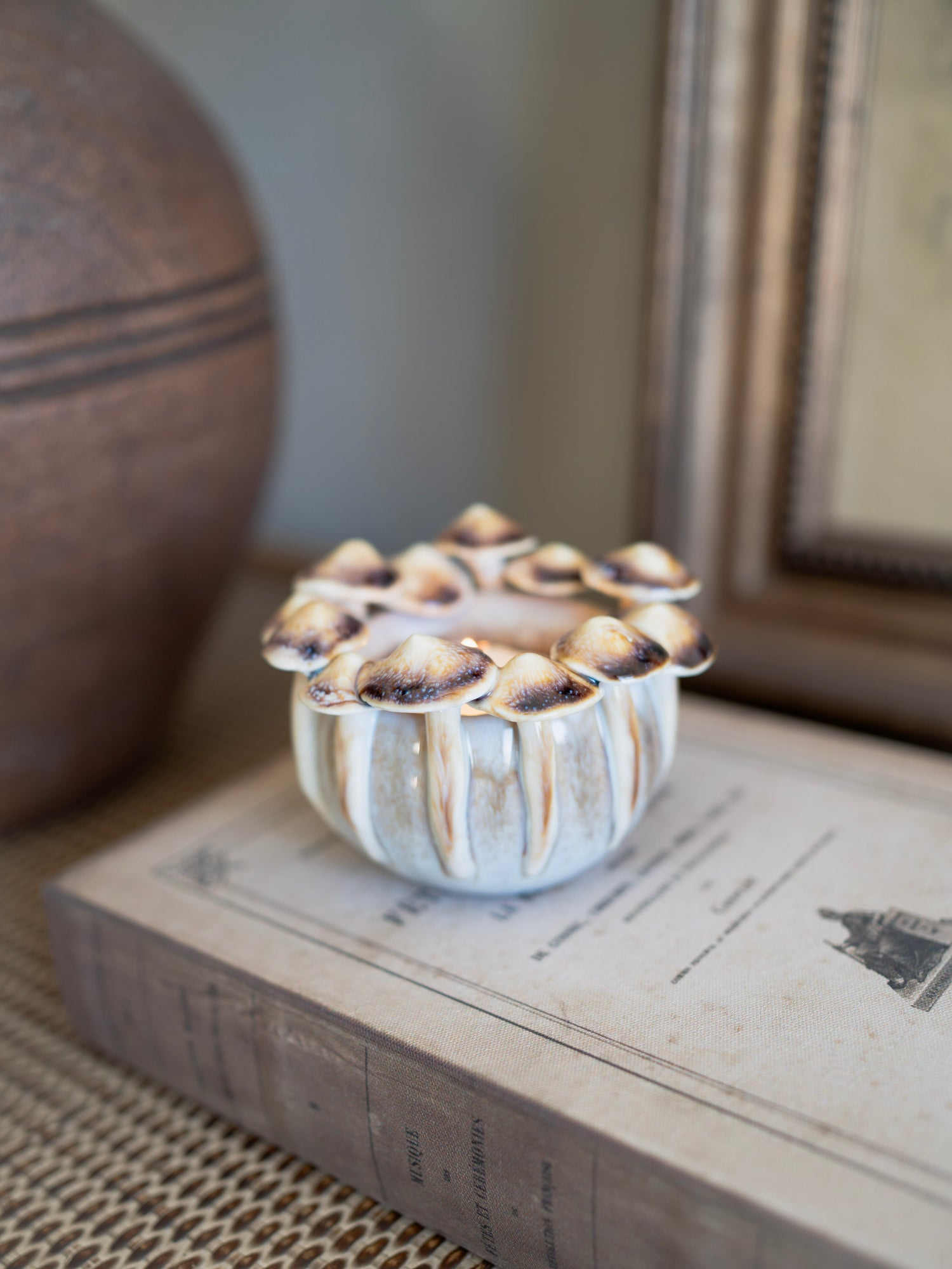 Decorative ceramic mushroom candle holder with textured surface on a book