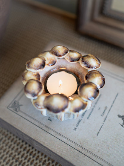 Ceramic candle mushroom holder with a lit candle on an old book