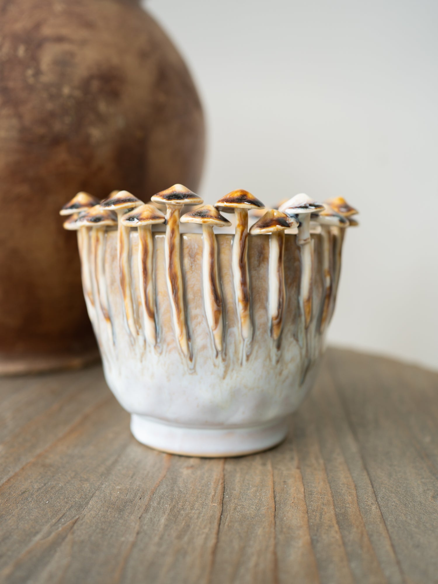 Ceramic beige glazed toadstool planter with textured surface on a wooden surface