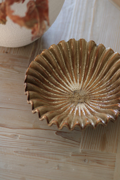 Decorative ceramic bowl with ruffle design on a wooden surface