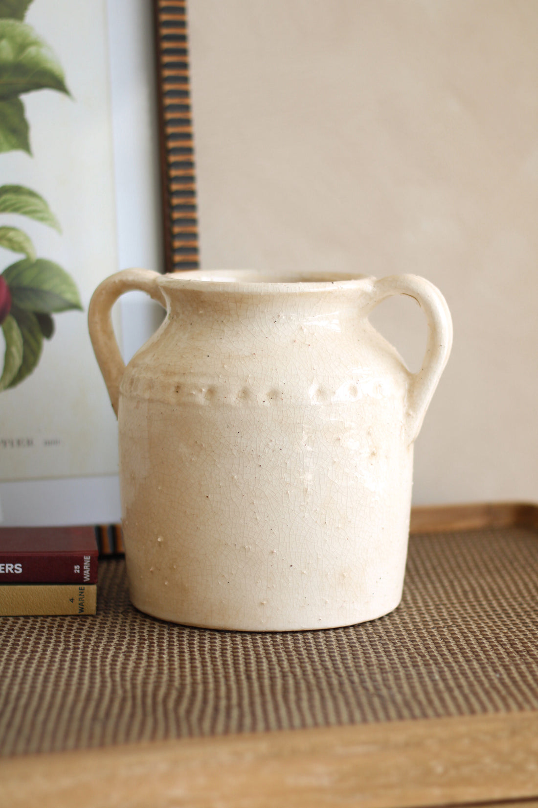 Beige ceramic vase with handles on a wooden surface