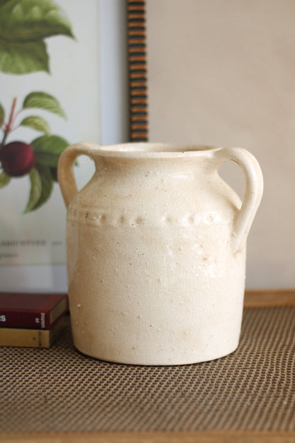 White ceramic vase with handles on a textured surface