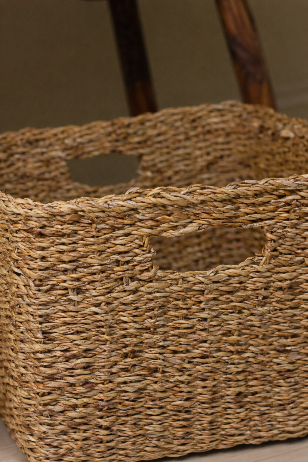 Close-up of a woven seagrass basket with a wooden chair in the background