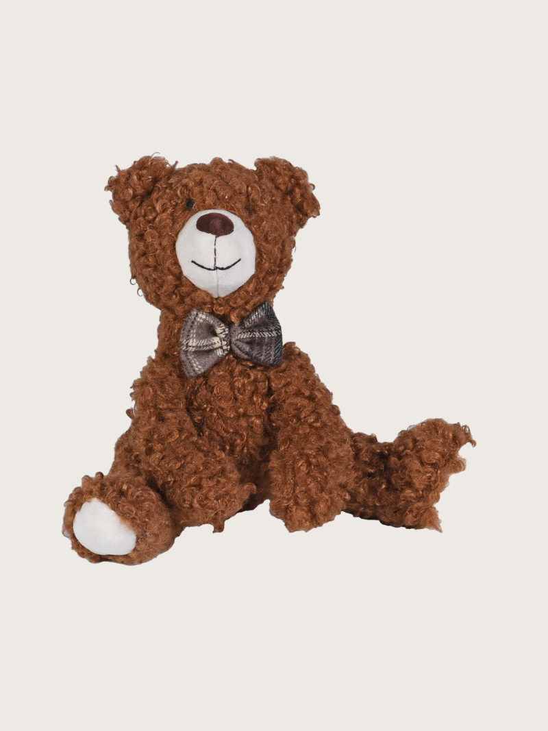Brown teddy bear with a bow tie on a light gray background