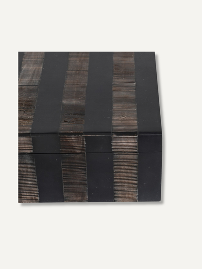 A rectangular black lacquered box with vertical dark brown wooden slat accents, photographed from an angled top-down view on a light off-white background.