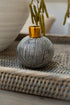 Ceramic vase with black and white pattern and gold top on woven surface