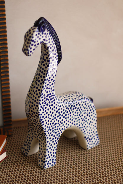 Decorative ceramic giraffe with blue and white pattern on a textured surface.