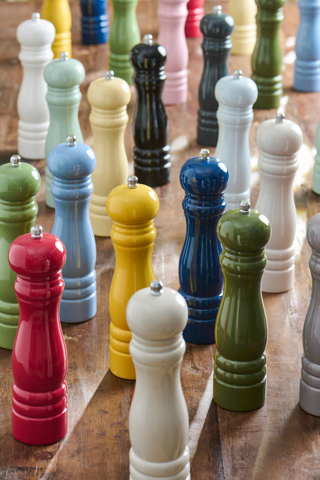 Colorful pepper mills arranged on a wooden surface