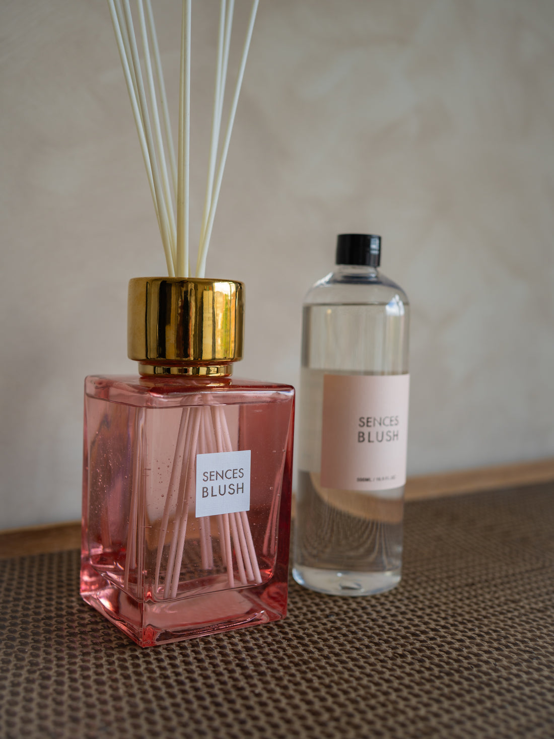 Pink diffuser bottle with gold cap and clear bottle labeled &