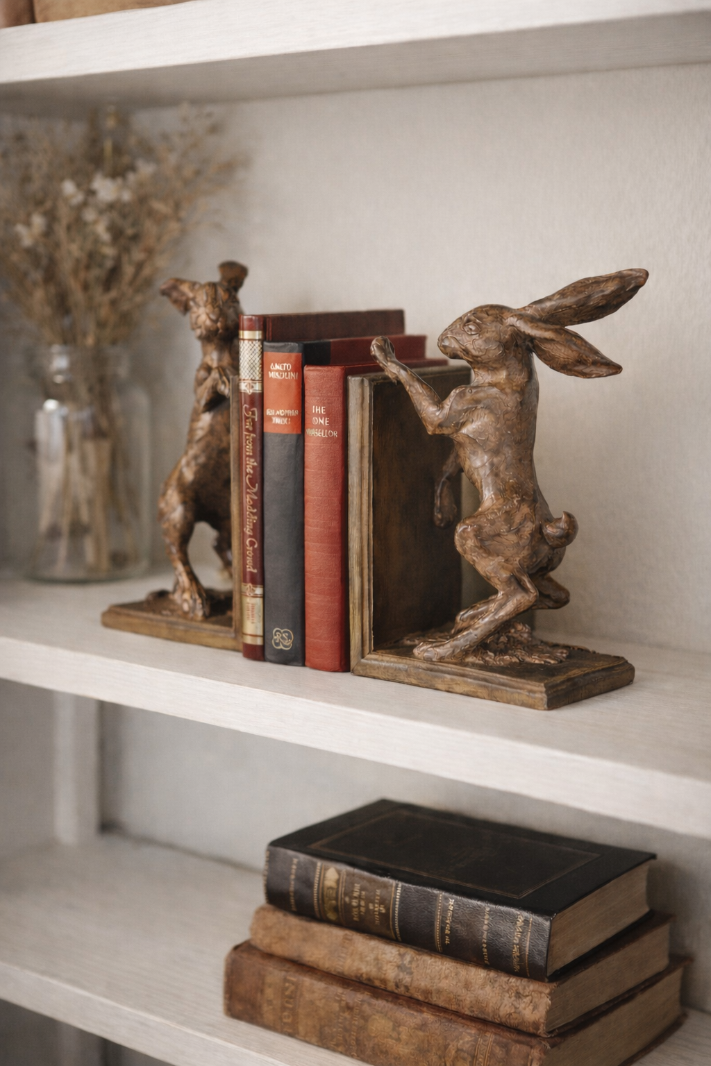 Decorative bookends shaped like boxing hares on a shelf with books.