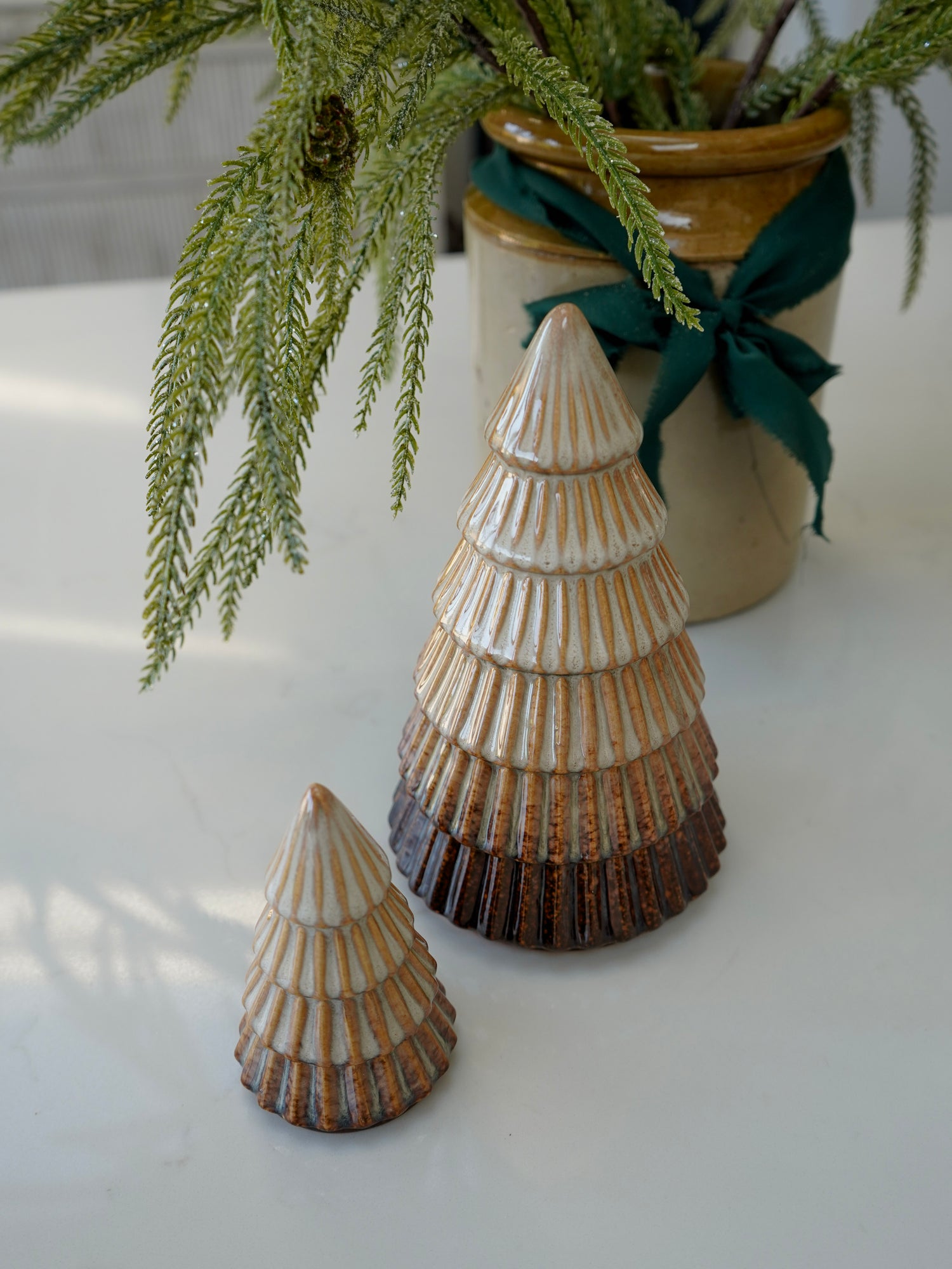 Two ceramic cone-shaped decorative items on a white surface with a plant in the background.
