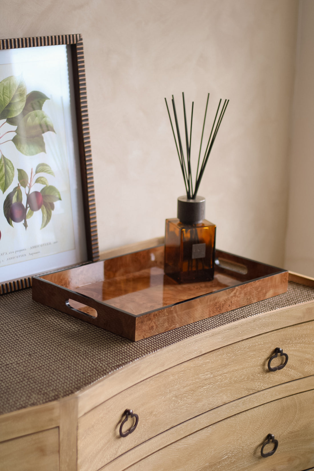 Decorative diffuser on a brown marbled effect tray with a framed picture in the background