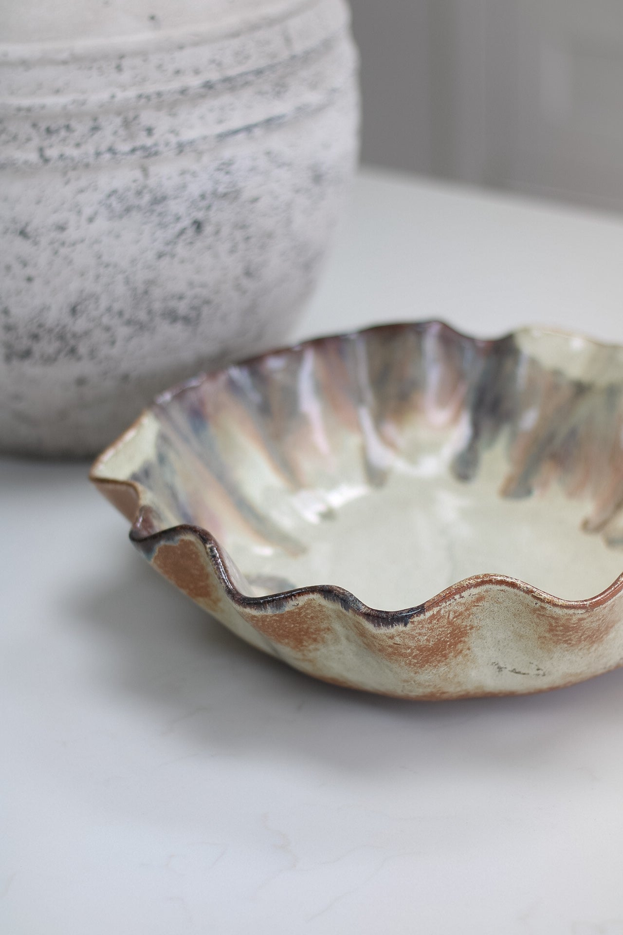 Ceramic brown ombre pleated bowl with wavy edge on a light surface