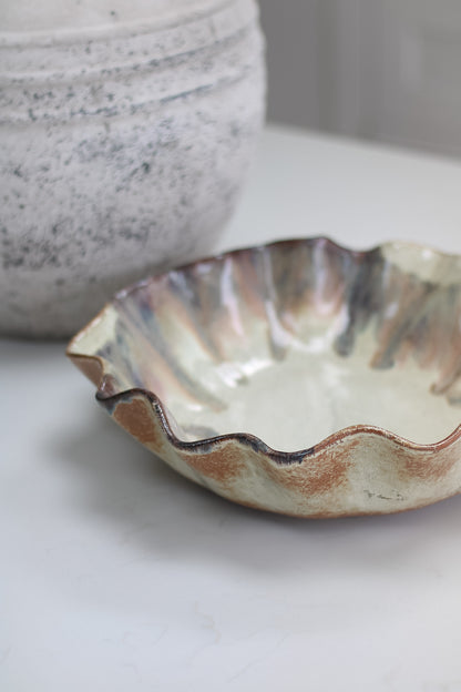 Ceramic brown ombre pleated bowl with wavy edge on a light surface