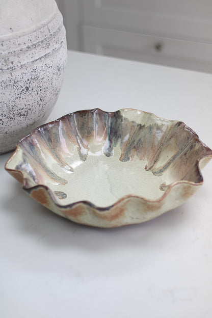 Ceramic brown pleated bowl with textured surface on a white background