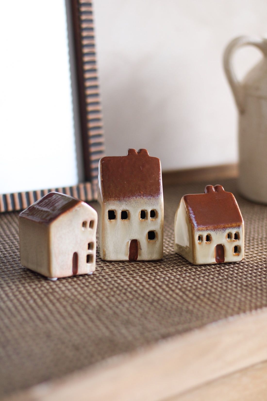 Three small ceramic houses on a textured surface with a blurred background