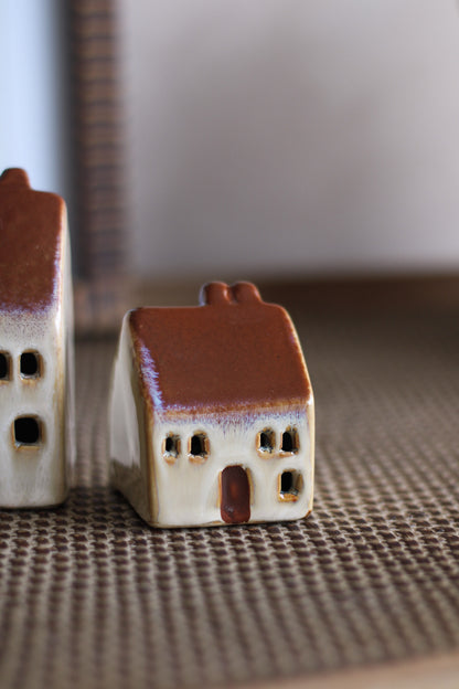 Two small ceramic houses on a textured surface with a blurred background
