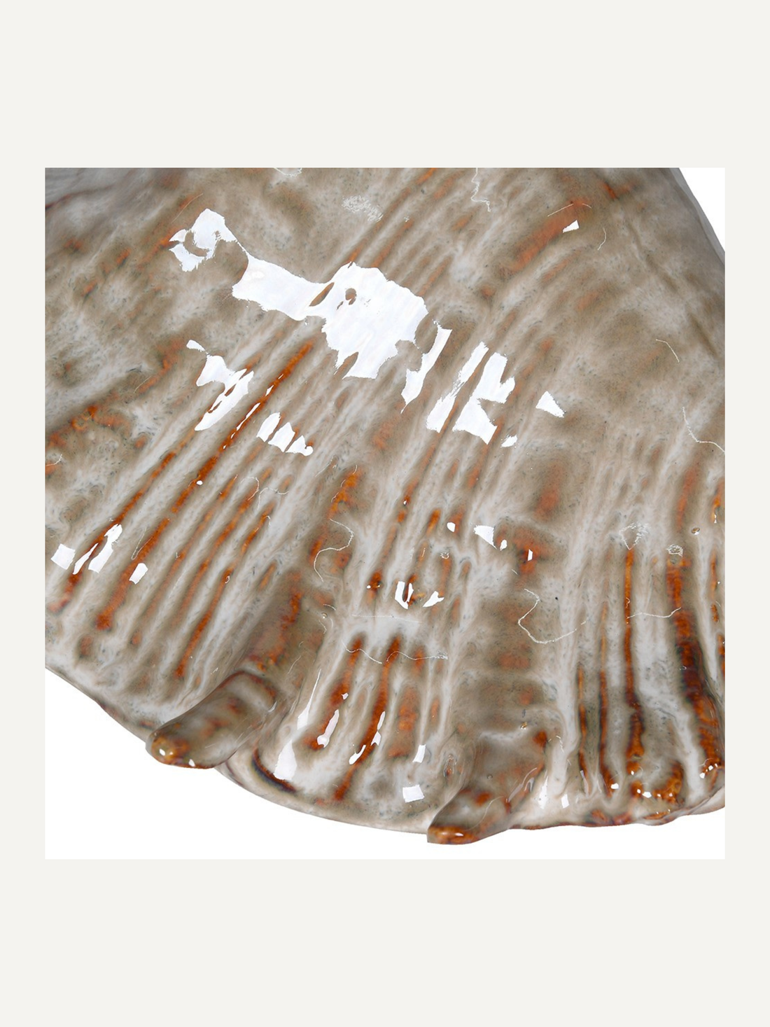 Close-up of a textured ceramic shell ornament with brown accents on a white background