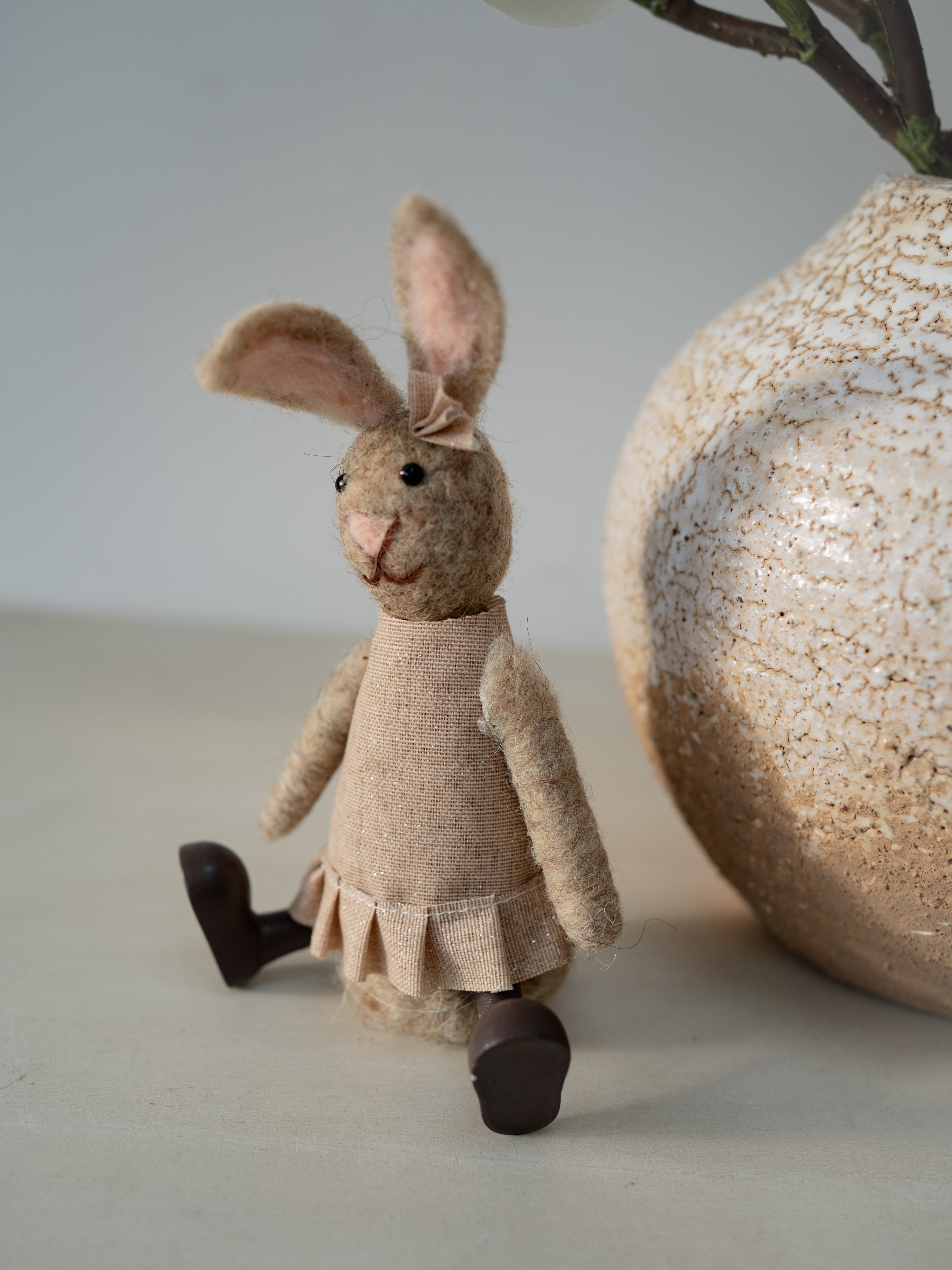 Textured rabbit figurine next to a decorative ball on a neutral background