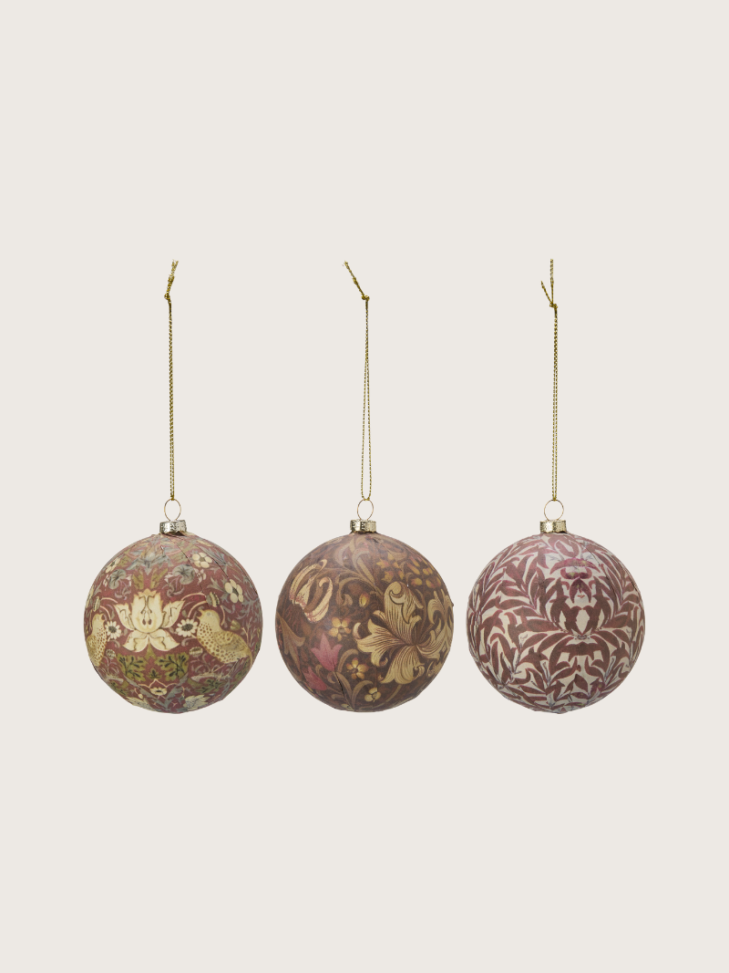 Three floral-patterned Christmas ornaments on a beige background