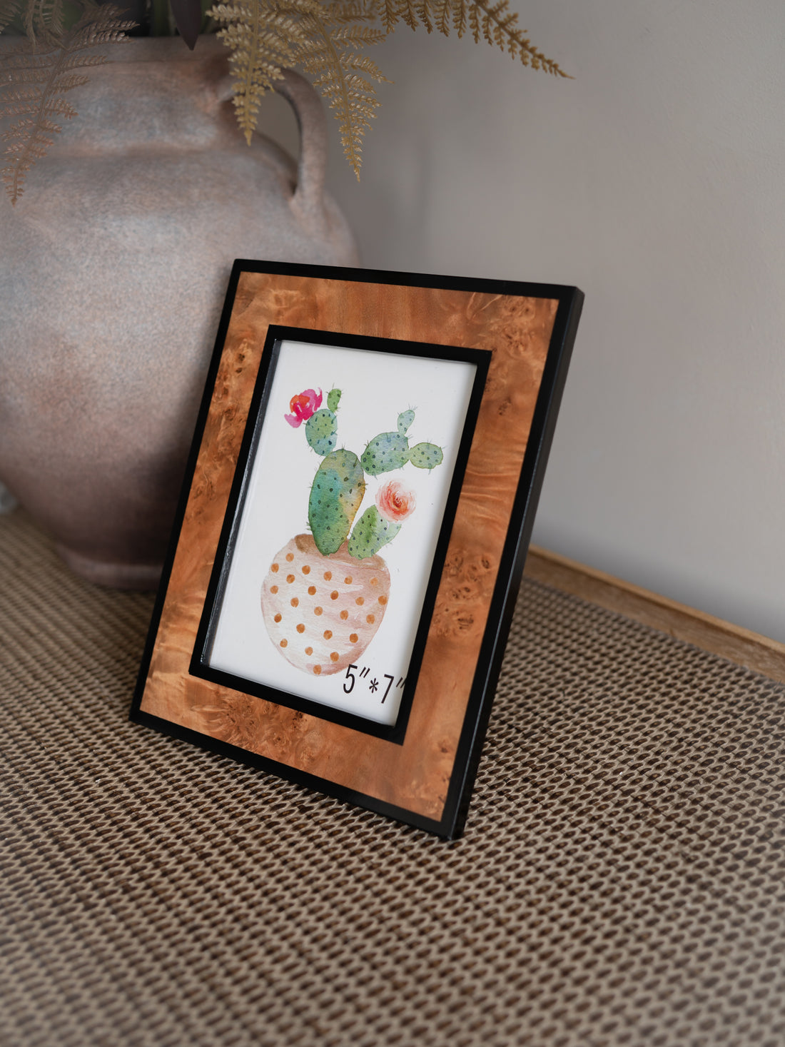 burl effect photo frame on a textured surface with a vase in the background.