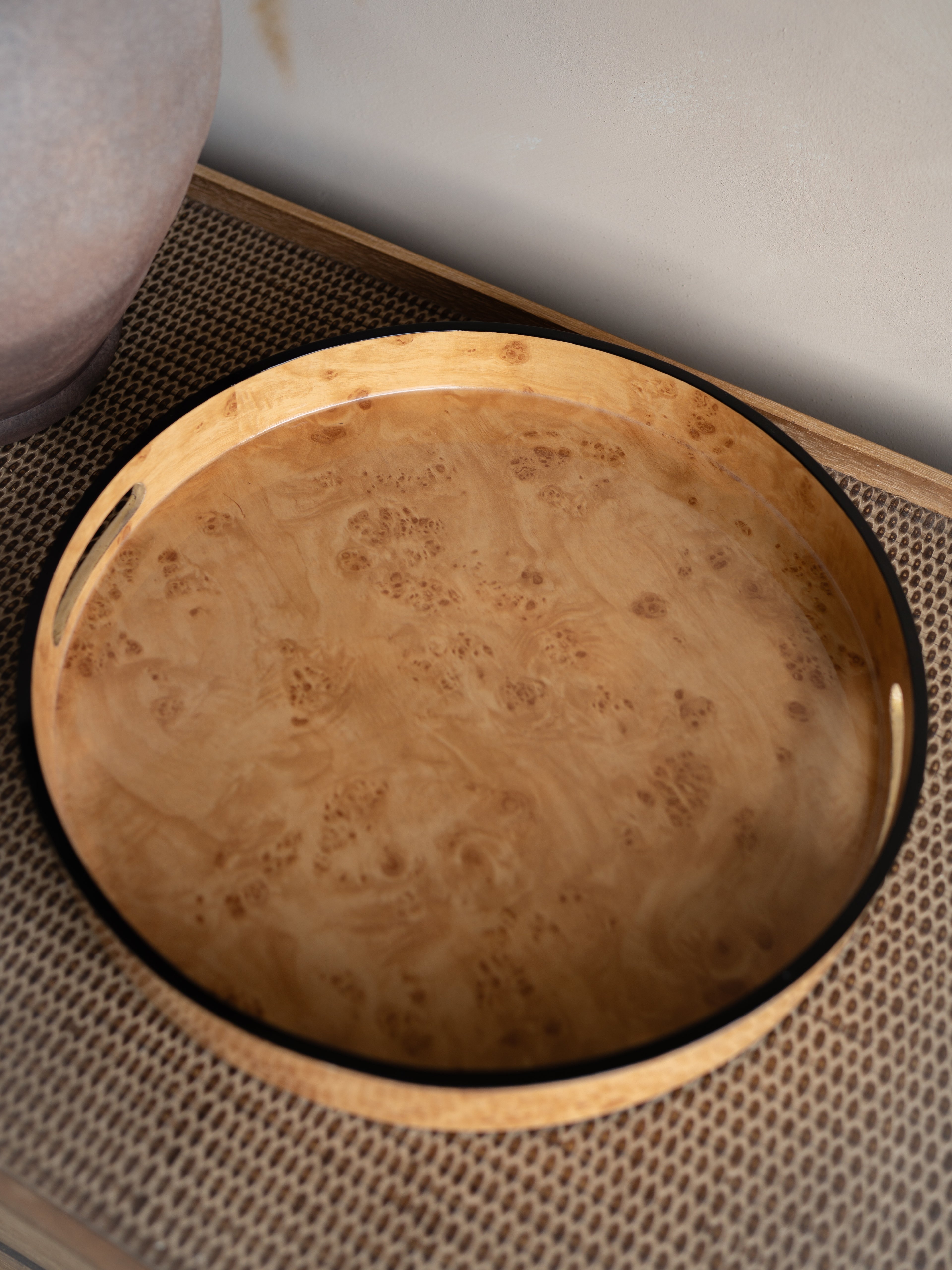 burl wood effect round tray with a textured surface on a woven mat