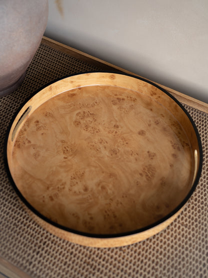 burl wood effect round tray with a textured surface on a woven mat