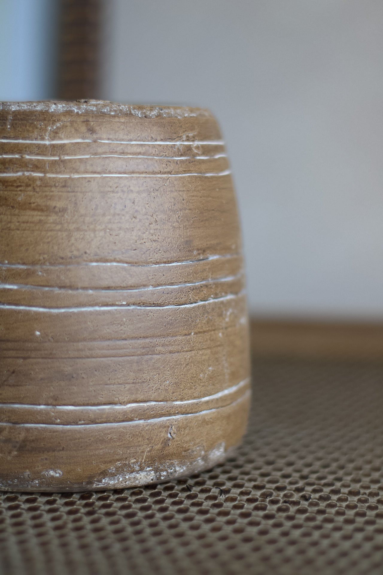 Close-up of a ceramic plant pot with a textured surface on a patterned surface.