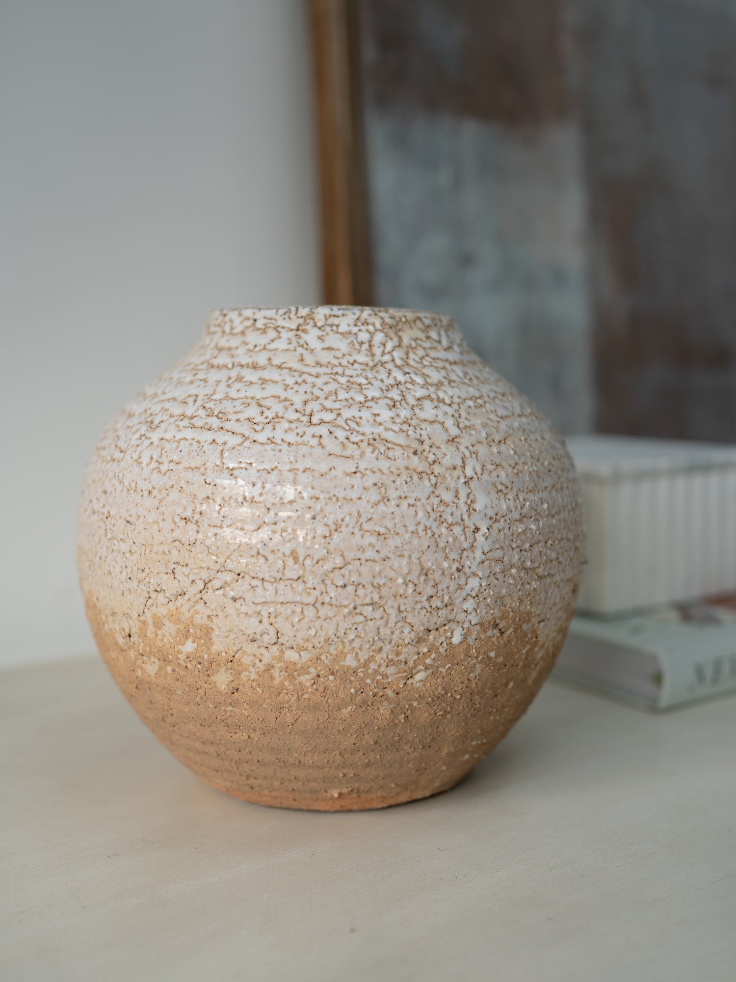 Textured ceramic vase on a neutral surface with a blurred background