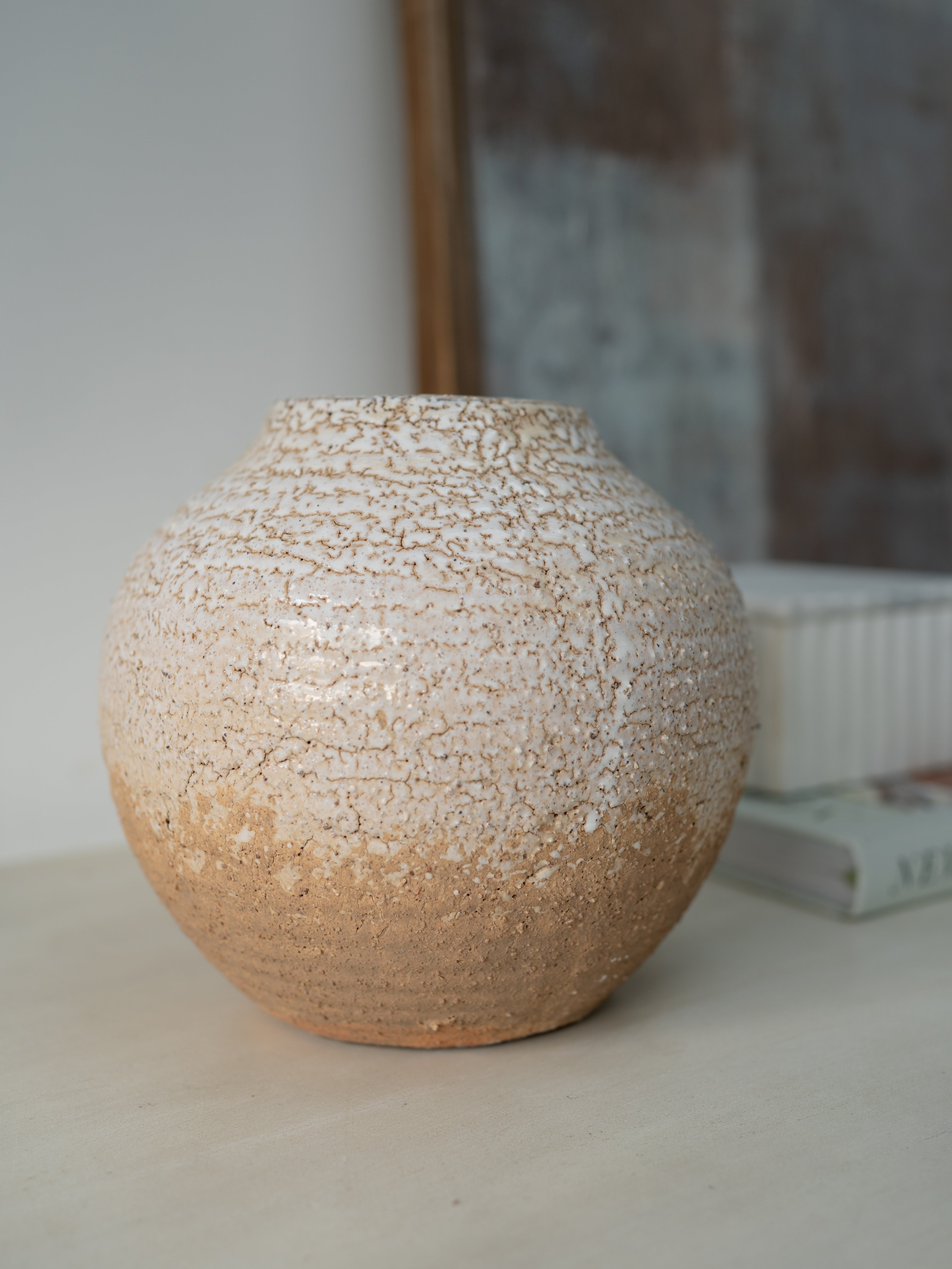 Textured ceramic vase on a neutral surface with a blurred background