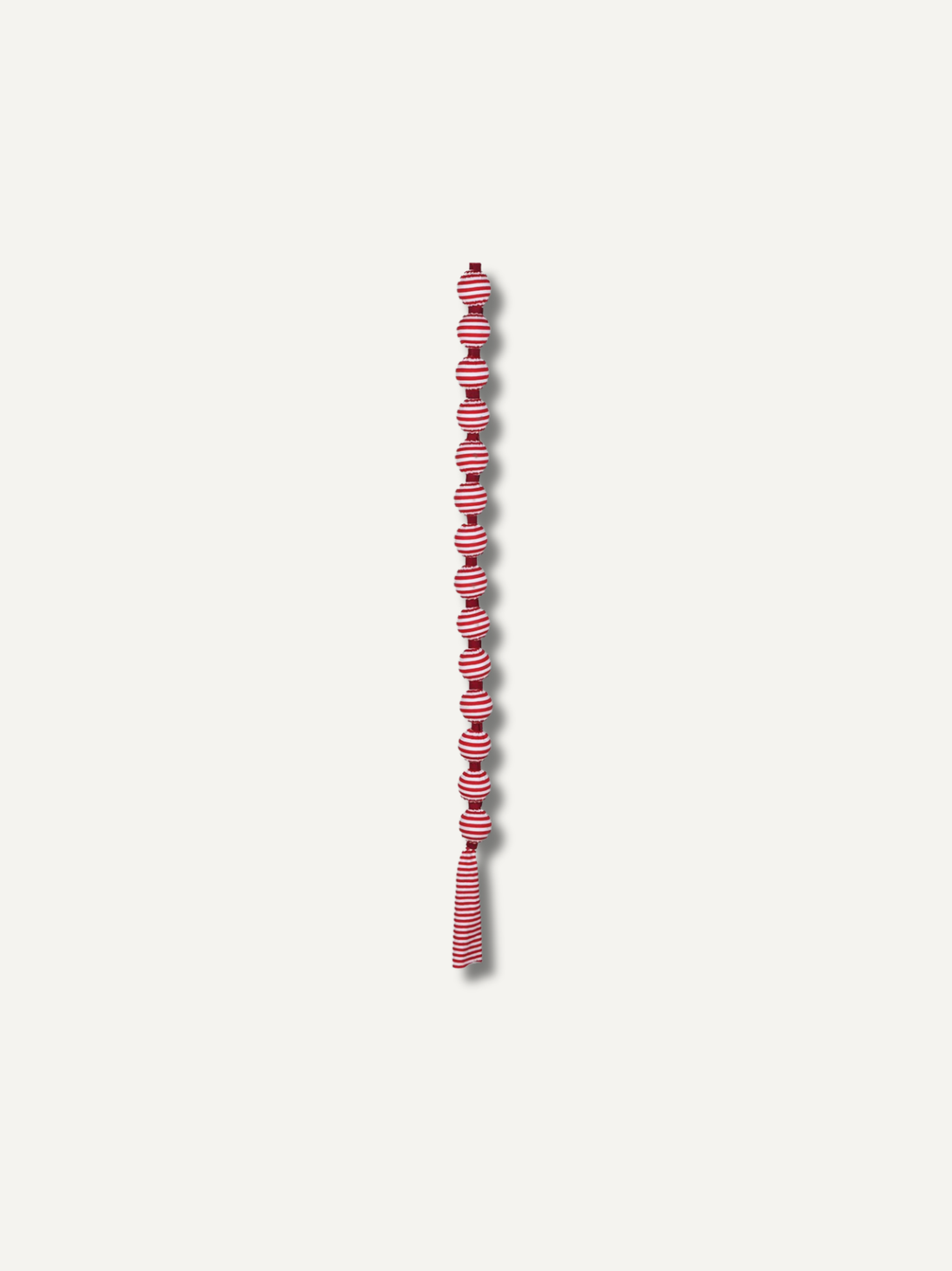 A long, narrow decorative garland or tassel strand with alternating candy cane red and white striped knotted sections, centered on a plain light gray background.