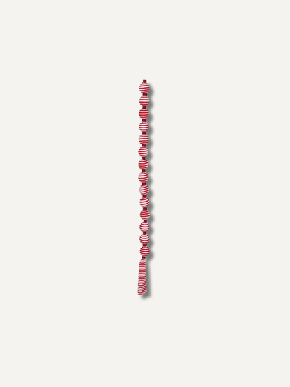 A long, narrow decorative garland or tassel strand with alternating candy cane red and white striped knotted sections, centered on a plain light gray background.