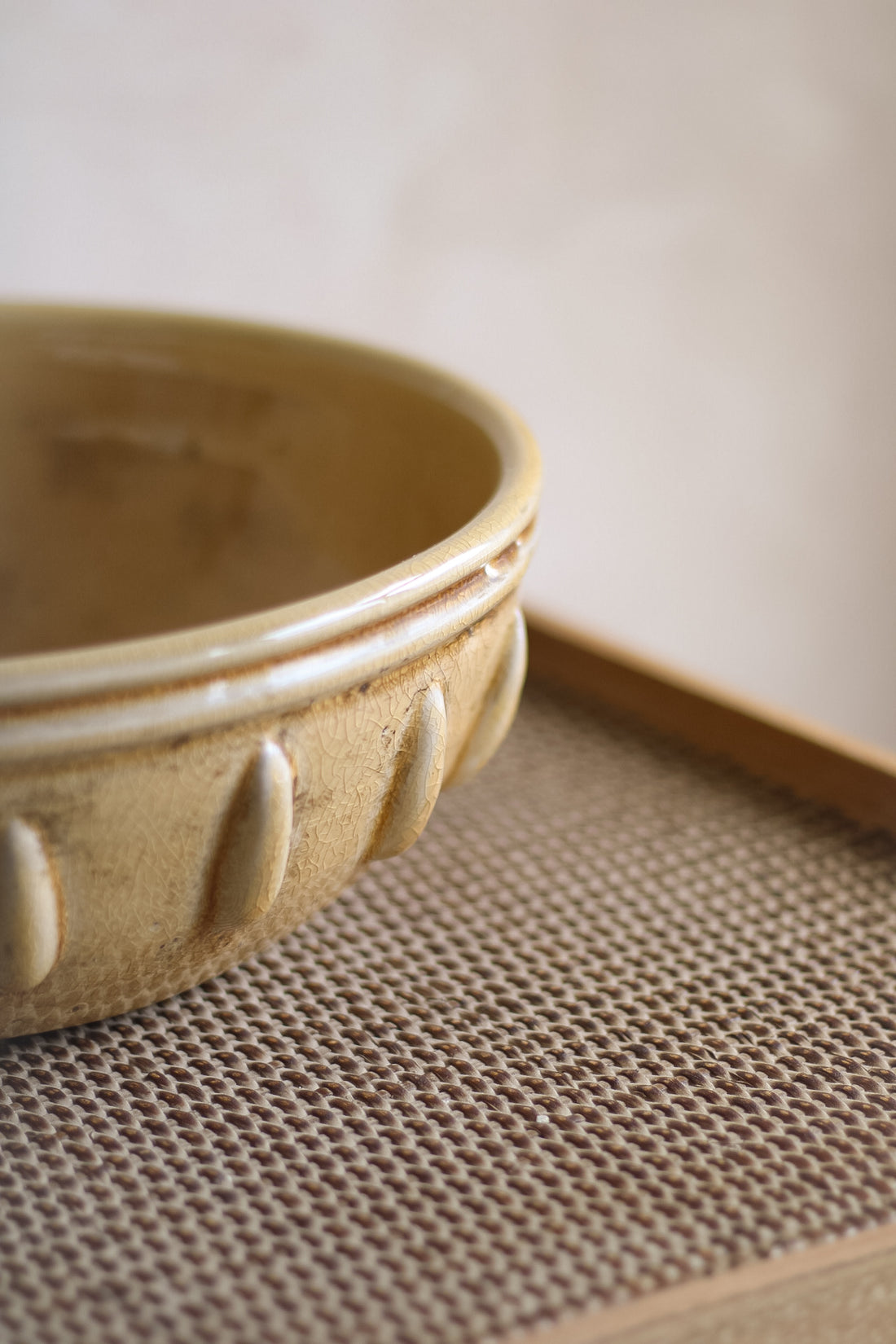 Mustard ceramic bowl on a textured surface with a neutral background