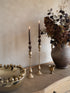 Decorative setting with candles, a vase, and a bowl on a textured surface.