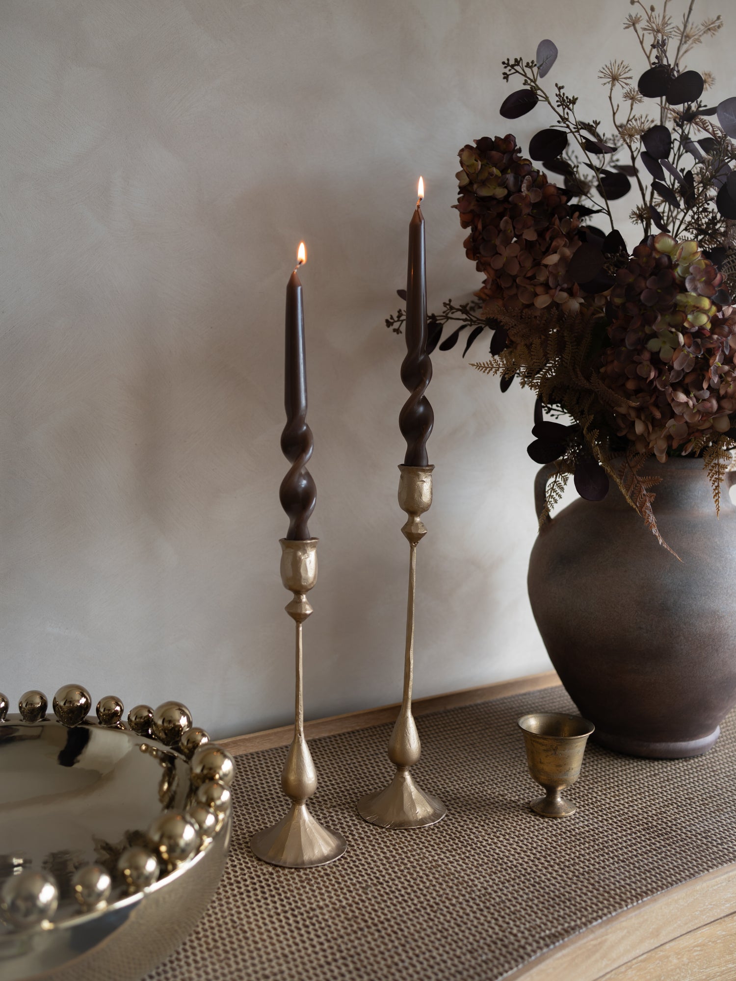 Decorative candles and vases on a textured surface with a neutral background