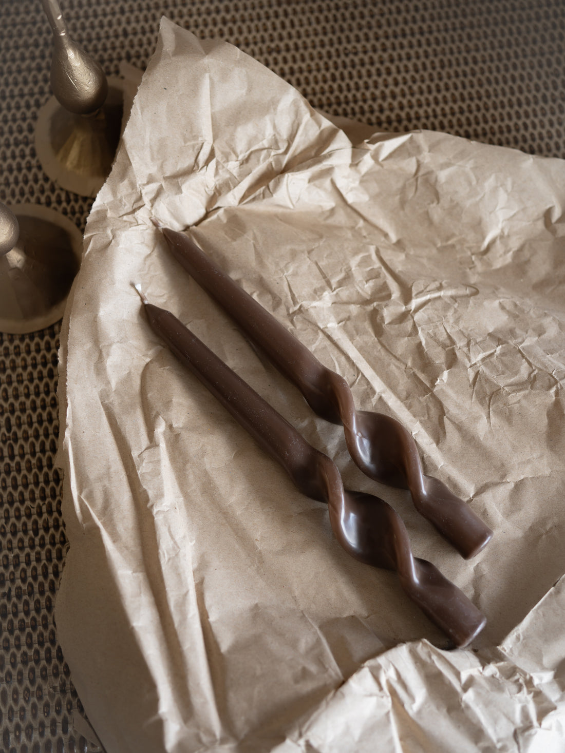 caramel dinner candles on crumpled brown paper with a textured background