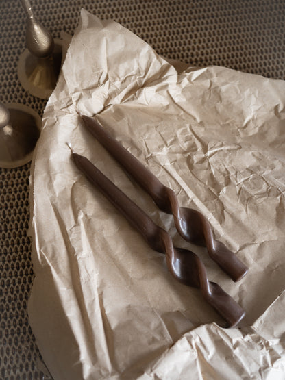 caramel dinner candles on crumpled brown paper with a textured background