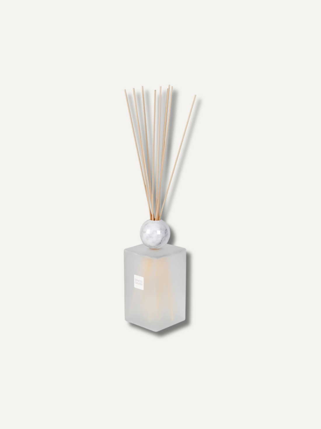 A reed diffuser with a frosted glass bottle, a white marble sphere, and natural bamboo reeds, shown against a solid off-white background.