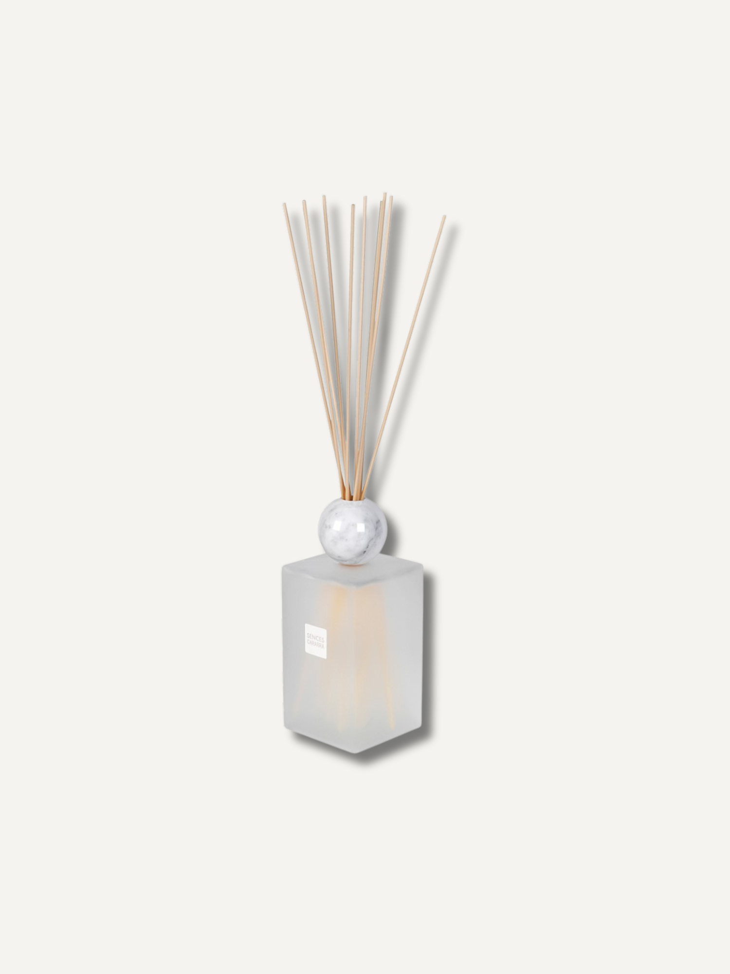 A reed diffuser with a frosted glass bottle, a white marble sphere, and natural bamboo reeds, shown against a solid off-white background.