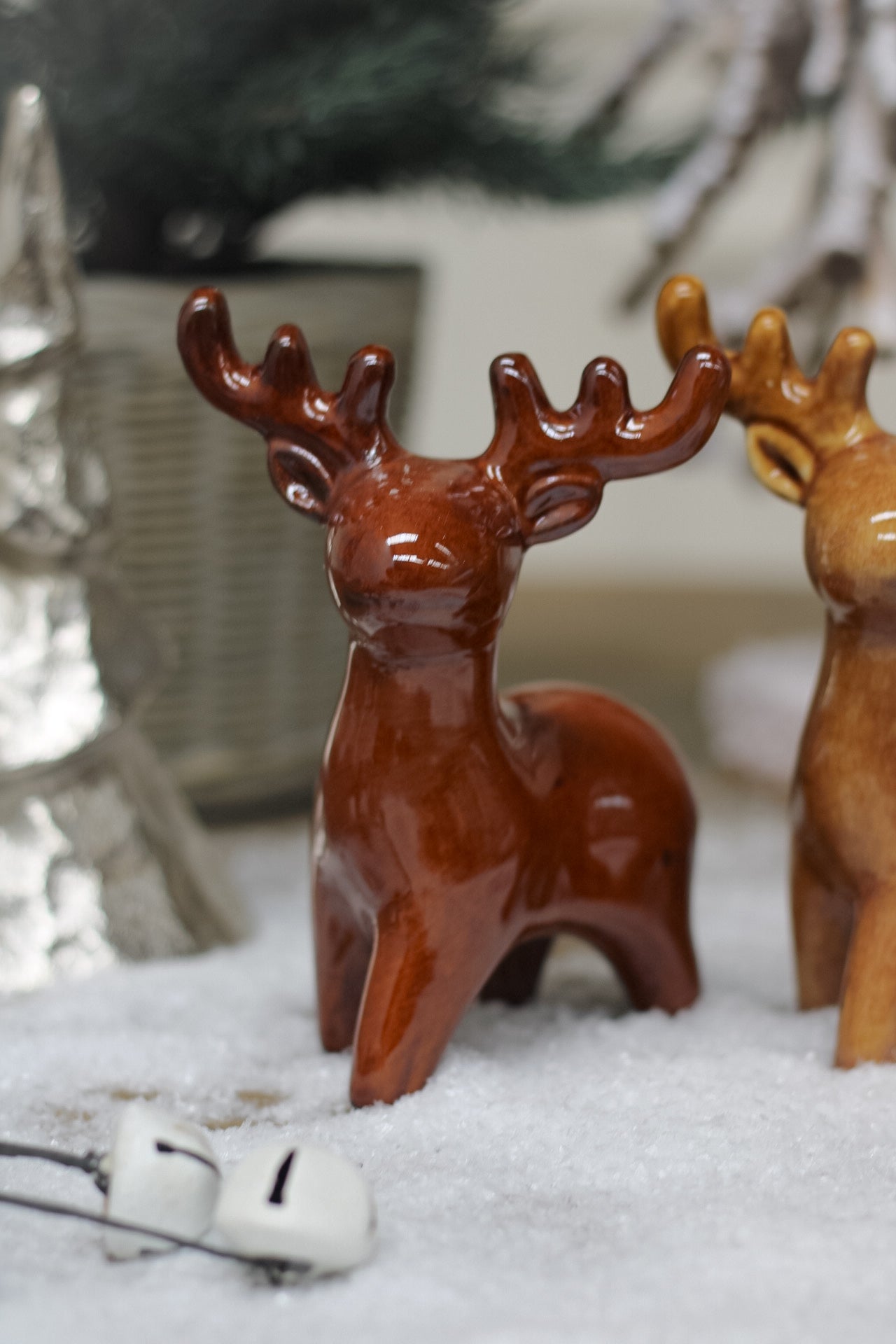 rich brown ceramic reindeer on snowy wooden table