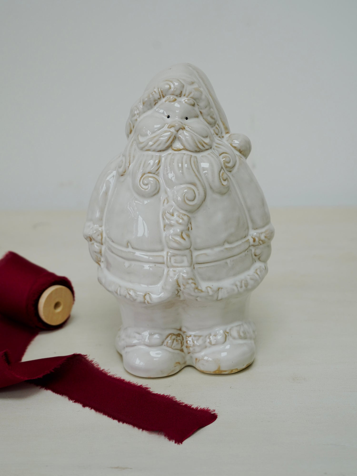 White ceramic Santa Claus figure with red ribbon on a white background